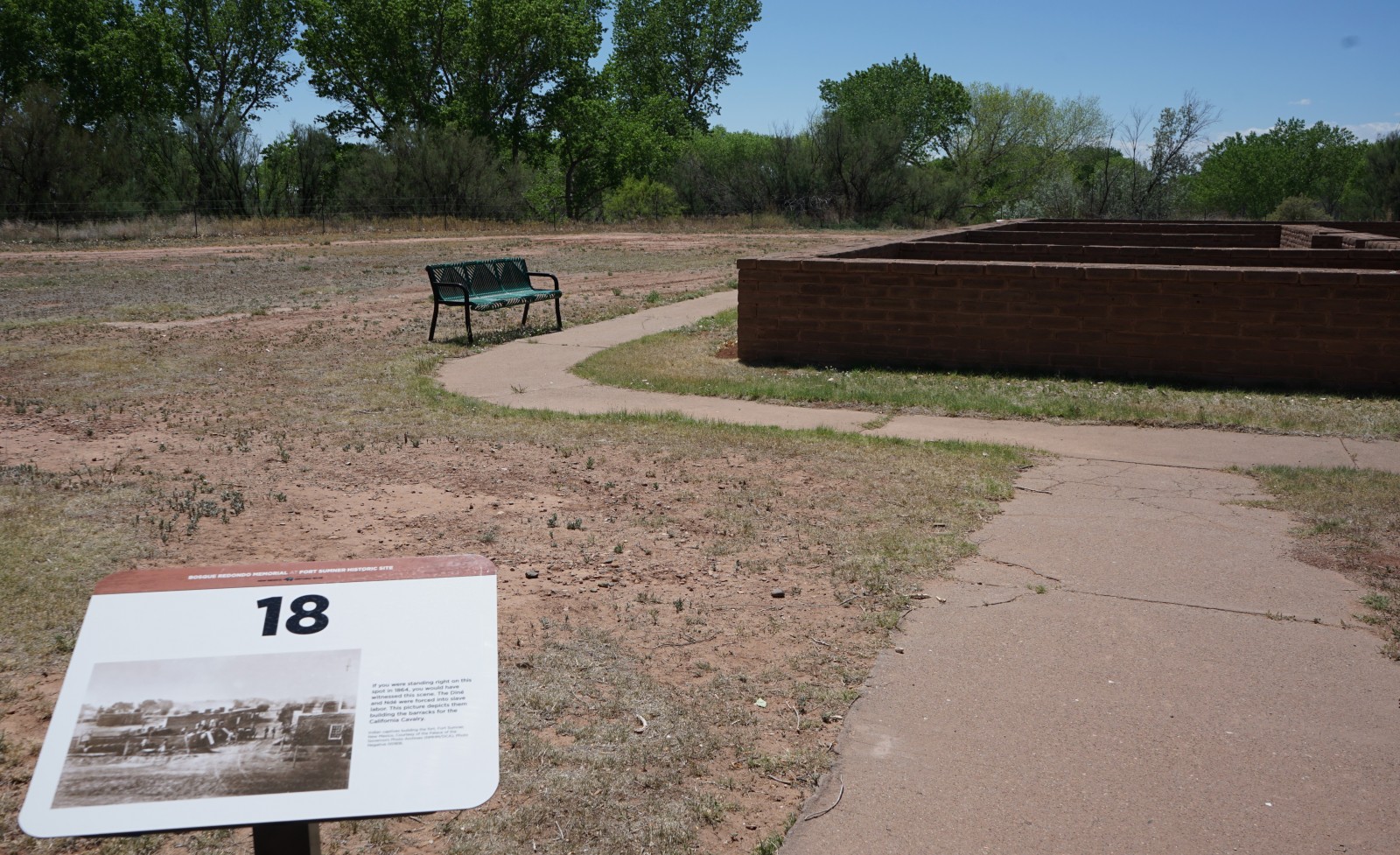 Bosque Redondo Memorial Audio Tour Stop 18, Fort reconstruction and green bench in the foreground.