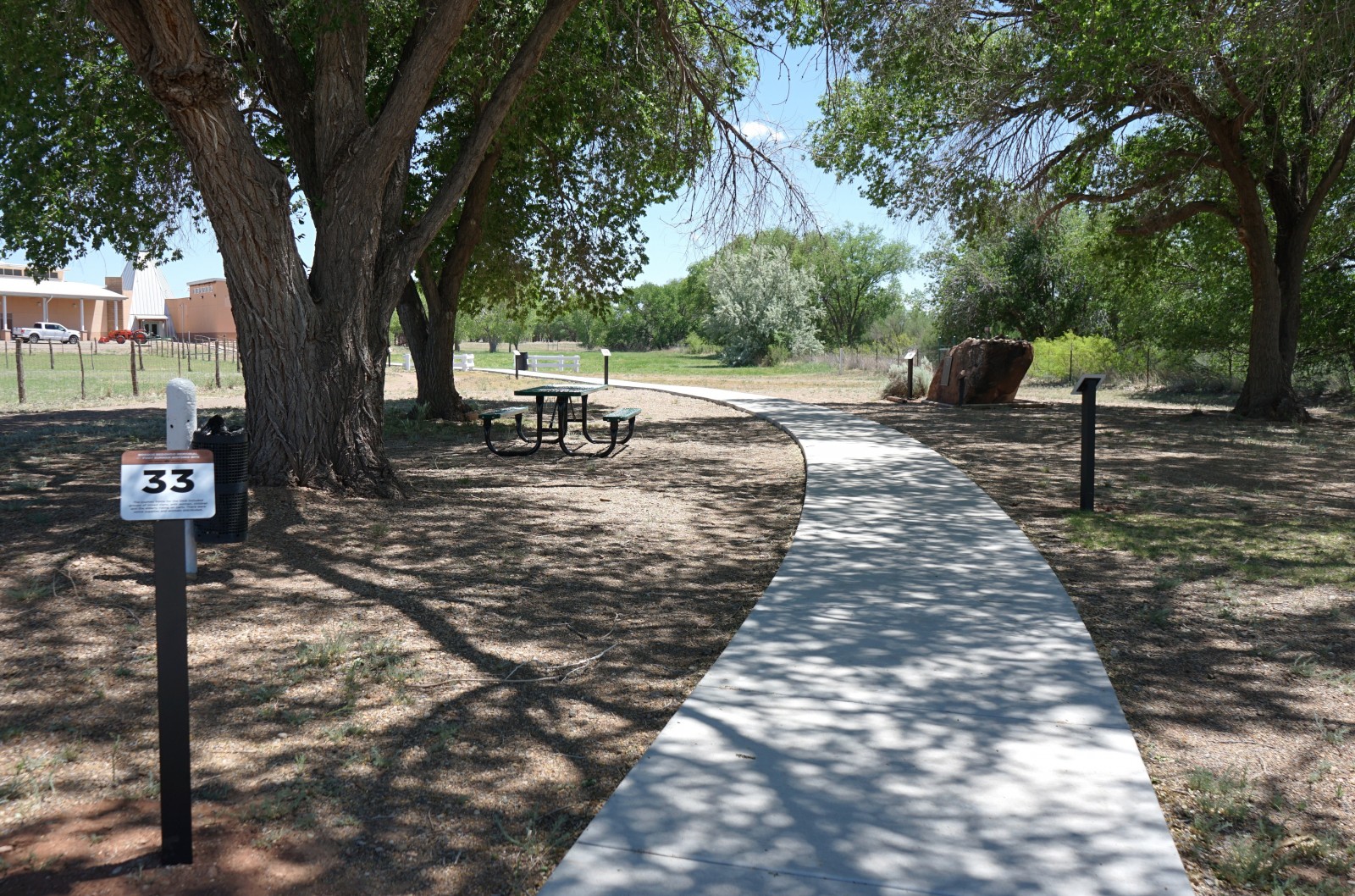 Bosque Redondo Memorial Audio Tour Stop 33, next to walkway with tree cover.